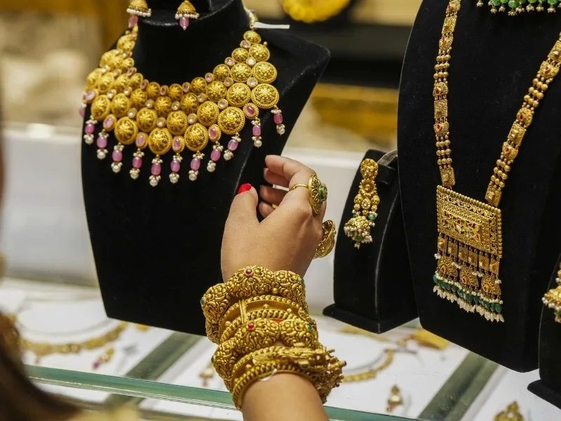 Women selecting gold ornaments in Andhra Pradesh jewelry store amid price drop, 2025