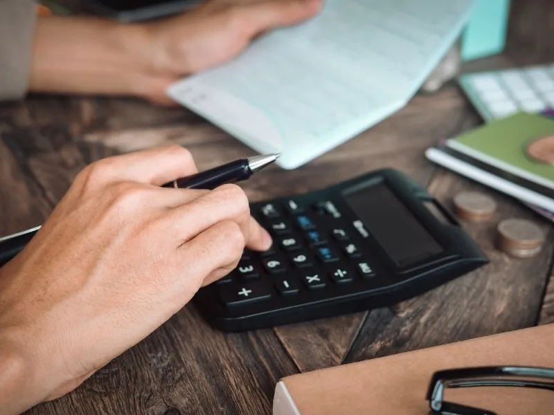 Person planning credit card debt repayment with calculator, 2025