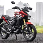 Honda CB200X in Sports Red parked on city street with adventure-style half-fairing
