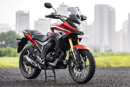 Honda CB200X in Sports Red parked on city street with adventure-style half-fairing