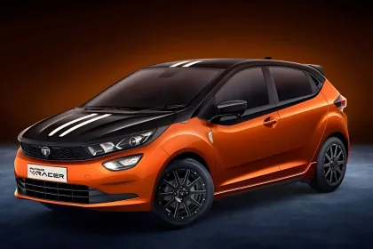 Tata Altroz Racer in Atomic Orange parked on city street with sharp LED headlights and R16 alloy wheels