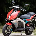 TVS X electric scooter in Red with blue inserts parked on city street with LED lighting
