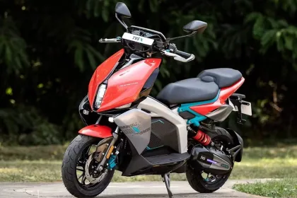 TVS X electric scooter in Red with blue inserts parked on city street with LED lighting