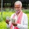 Farmer checking PM-KISAN 20th installment status on smartphone, expected to be credited on June 20, 2025.
